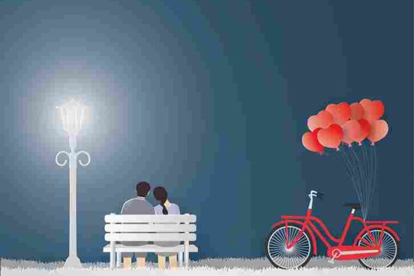 Two people sit close together on a bench beside a bicycle carrying heart-shaped balloons